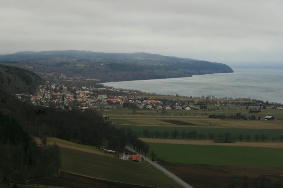 a large body of water sitting next to a lush green hillside